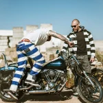 Biker portant le pantalon rayé bleu et blanc Hold Fast sur une moto vintage