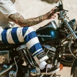 Pantalon biker rayé bleu porté sur une moto, détail du revers Hold Fast