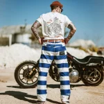 Pantalon rayé bleu et blanc porté de dos à côté d’une moto custom