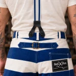 Gros plan de la fixation arrière des bretelles 1937 Heavy Duty, patte unique en cuir noir cousue à la sangle et boutons du pantalon bleu